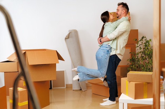 Jeune couple heureux dans la chambre avec des boîtes de déménagement dans une nouvelle maison