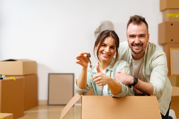 Jeune couple heureux dans la chambre avec des boîtes de déménagement dans une nouvelle maison