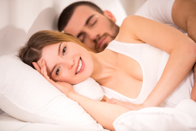 Jeune couple heureux dans un lit blanc à la maison.