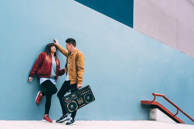 Jeune couple heureux dansant dans la rue avec une radio cassette stéréo vintage xA