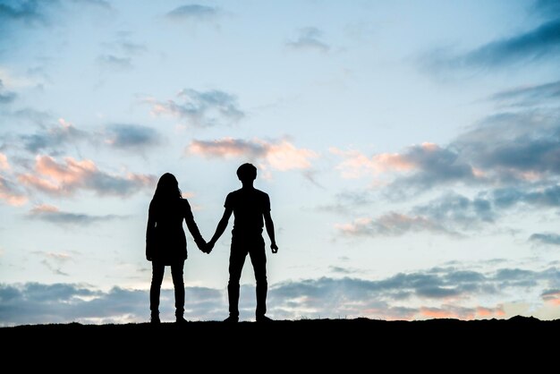Un jeune couple heureux ensemble contre un magnifique coucher de soleil Concept de jouissance de la liberté