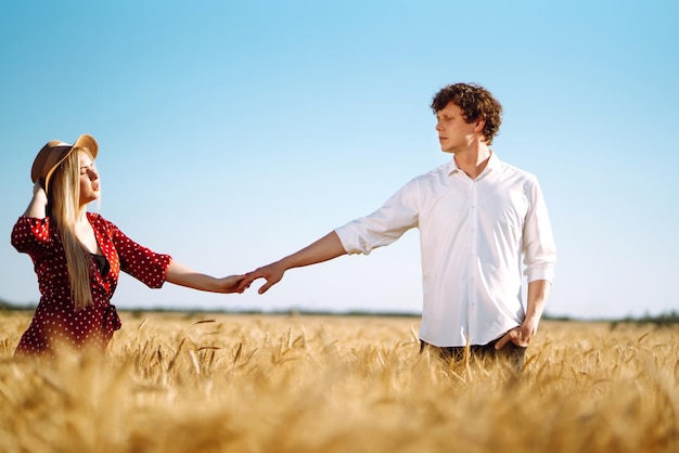 Jeune couple heureux étreignant sur un champ de blé au coucher du soleil Profitant du temps ensemble