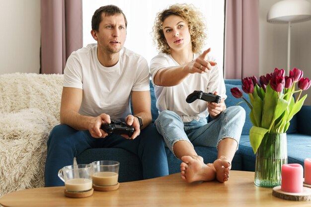 Un jeune couple heureux avec une manette de jeu joue à la console de jeux vidéo