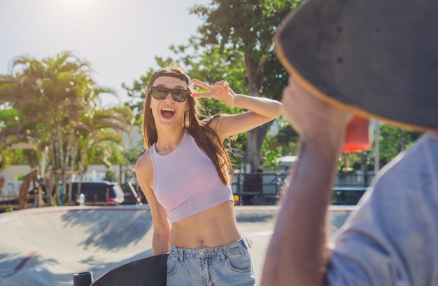 Un jeune couple heureux avec des planches à roulettes profite du longboard au skatepark