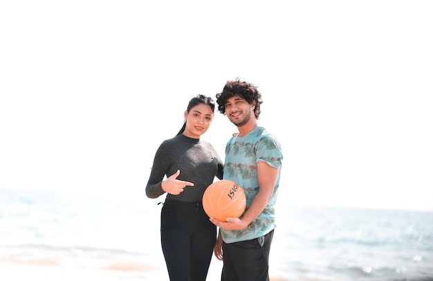 jeune couple heureux pose avant tenant le football sur la plage modèle pakistanais indien