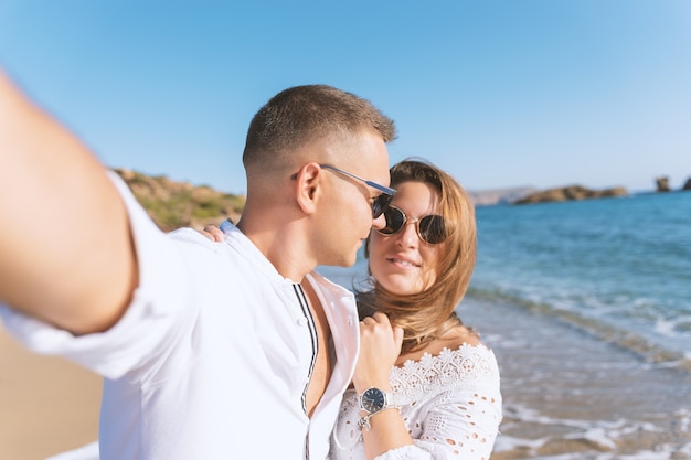 Jeune couple heureux prenant selfie sur la plage