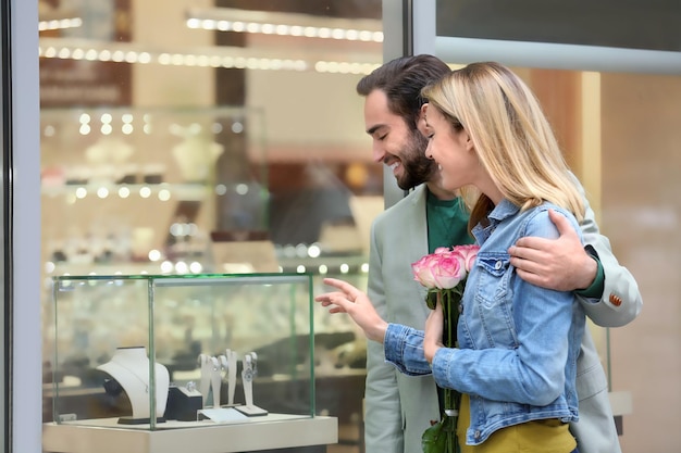 Jeune couple heureux près de la vitrine de la bijouterie