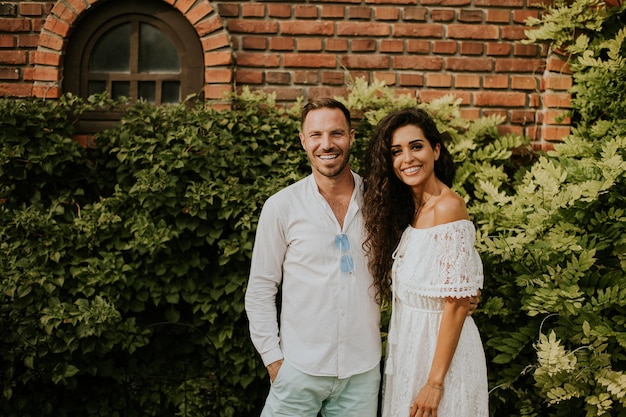 Un jeune couple heureux profite du cadre magnifique d'un jardin qui se prélasse au soleil et de la compagnie de l'autre