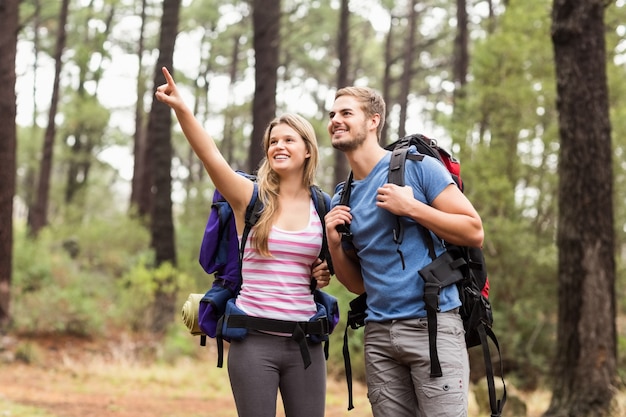 Jeune couple heureux randonneur pointant au loin