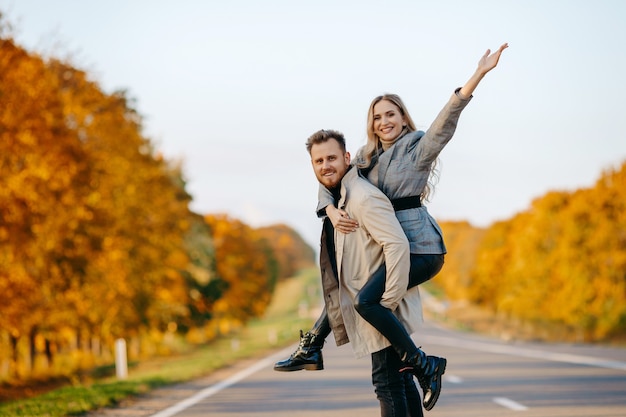 Un jeune couple heureux sur une route d'automne