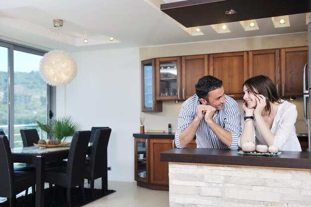 un jeune couple heureux s'amuse dans une cuisine en bois moderne à l'intérieur tout en préparant des aliments frais