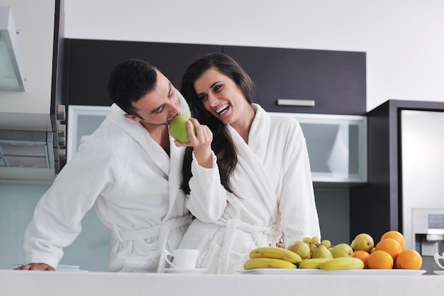 un jeune couple heureux s'amuse dans une cuisine moderne à l'intérieur tout en préparant une salade de fruits et légumes frais