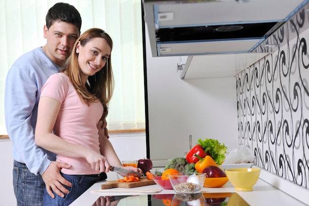 un jeune couple heureux s'amuse tout en préparant des aliments frais et sains dans la cuisine