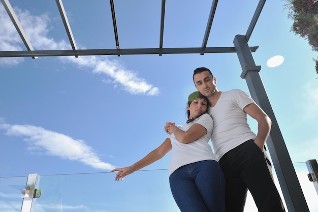 un jeune couple heureux se détend sur un balcon extérieur avec l'océan et le ciel bleu en arrière-plan
