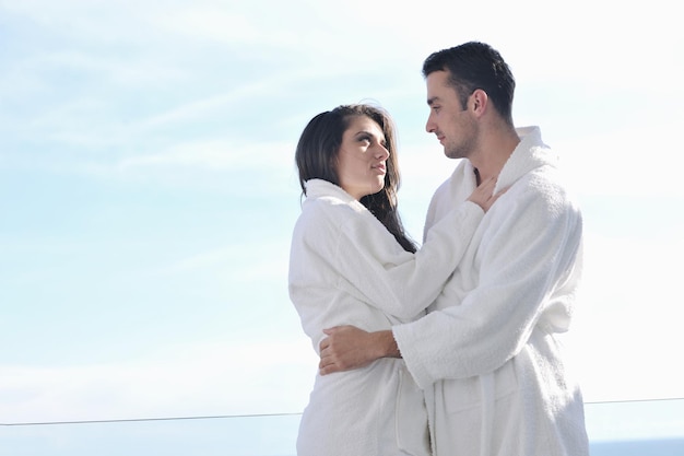 un jeune couple heureux se détend sur un balcon extérieur avec l'océan et le ciel bleu en arrière-plan