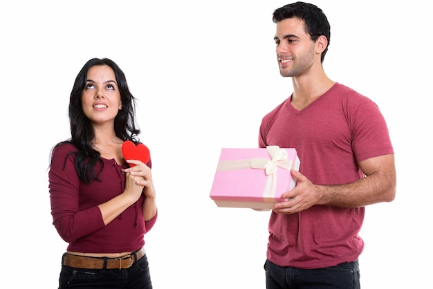 Jeune couple heureux souriant avec homme donnant une boîte-cadeau et une femme pensant