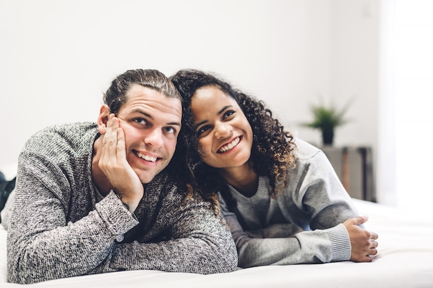 Jeune couple heureux sourire et s'amuser couché dans son lit ensemble à la maison