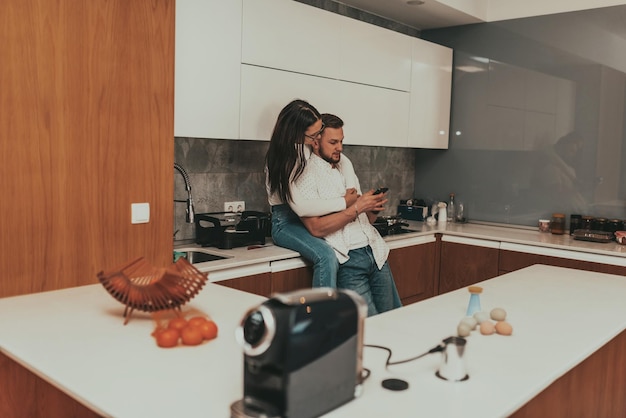 Un jeune couple heureux utilisant deux téléphones partage des actualités sur les réseaux sociaux à la maison, souriant, mari et femme, utilisateurs du millénaire, clients parlant de faire des achats en ligne assis à table, concept de style de vie de technologie mobile. Haut