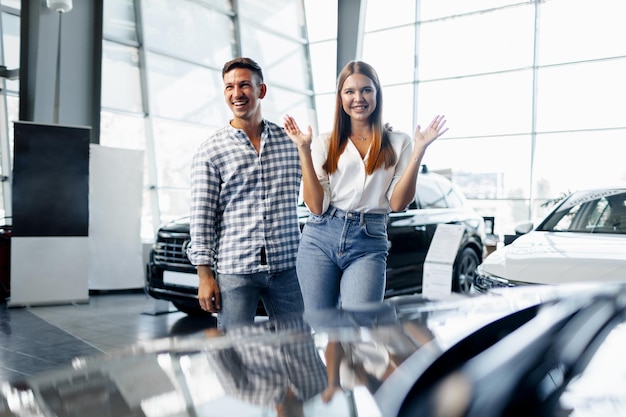 Un jeune couple heureux vient d'acheter une nouvelle voiture chez un concessionnaire