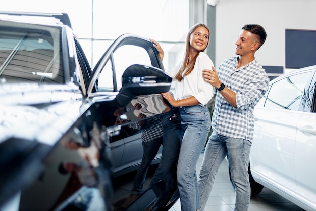 Photo un jeune couple heureux vient d'acheter une nouvelle voiture chez un concessionnaire