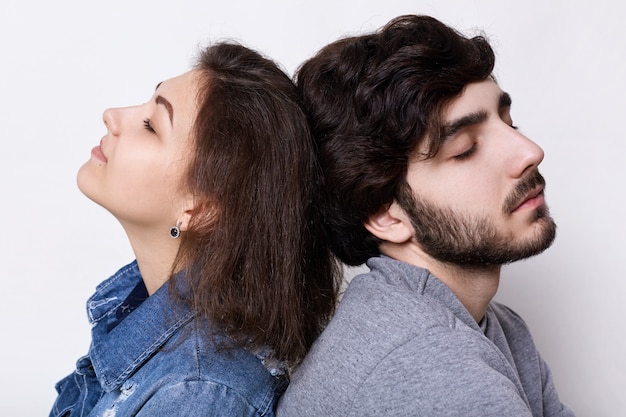 Un jeune couple hipster assis à la maison tête à tête se détendre avec les yeux fermés