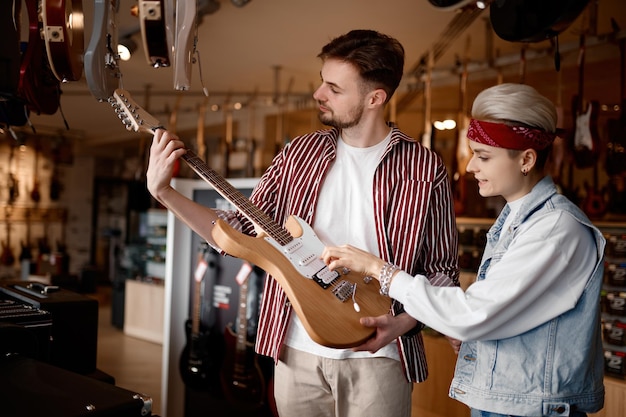 Jeune couple hipster à la recherche d'une nouvelle guitare électrique pour la performance