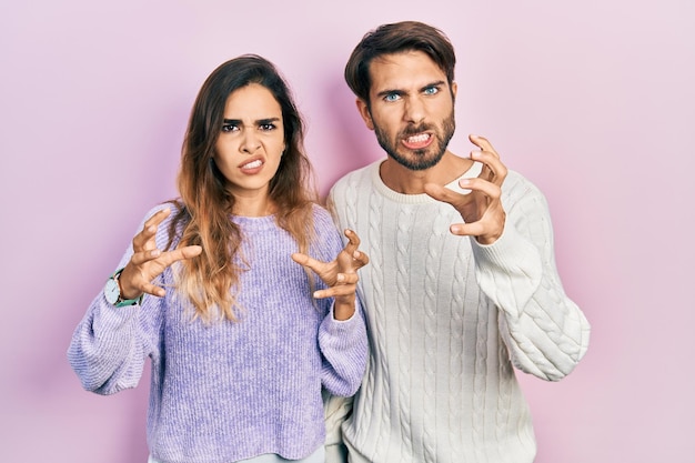 Jeune couple hispanique portant des vêtements décontractés criant frustré par les mains de rage essayant d'étrangler en criant fou
