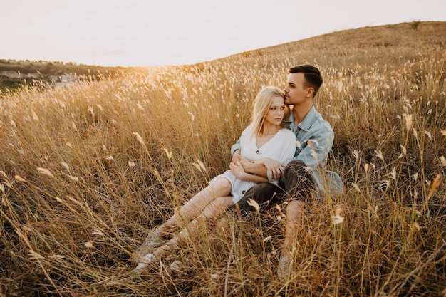 Jeune couple d'homme et femme assis dans un champ d'or, étreignant.