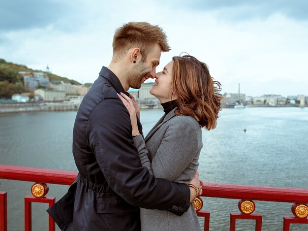 Jeune couple homme et femme debout sur le pont au bord de la rivière sur fond de paysage urbain