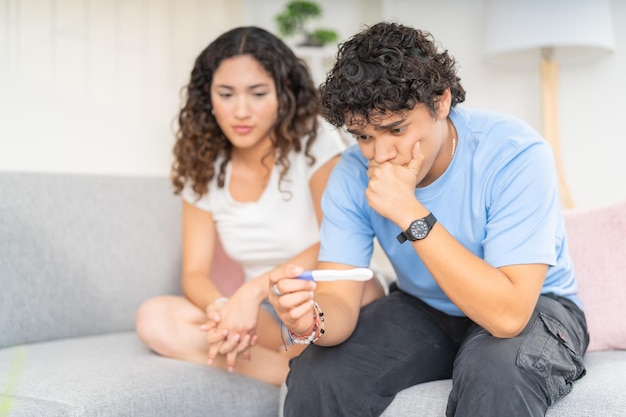 Photo jeune couple impatient attendant les résultats d'un test de grossesse assis sur le canapé