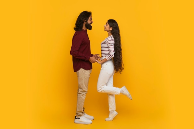 Un jeune couple indien émotionnel a une date sur un fond jaune.