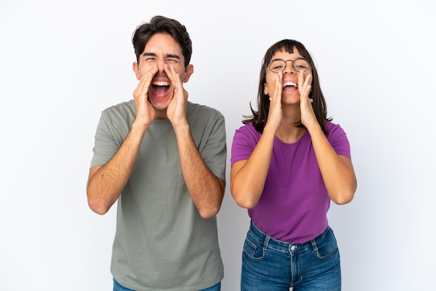 Jeune couple isolé sur fond blanc isolé criant et annonçant quelque chose