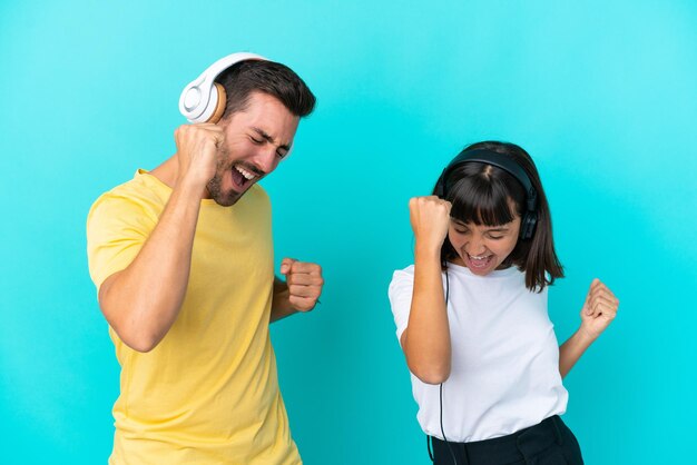 Jeune couple isolé sur fond bleu écoutant de la musique et dansant