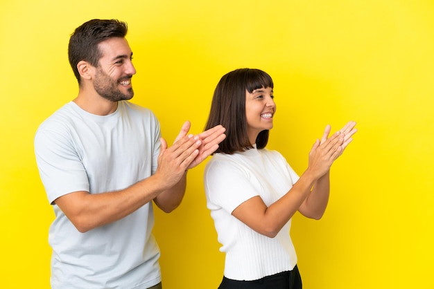 Jeune couple isolé sur fond jaune applaudissant après présentation lors d'une conférence