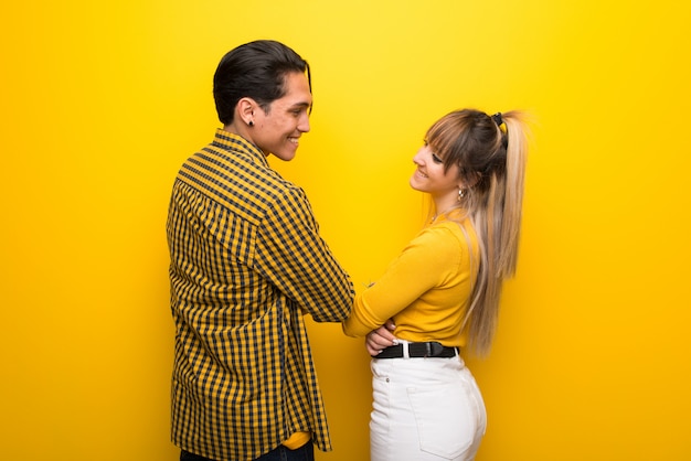 Jeune couple, sur, jaune, fond, regarder, épaule, sourire