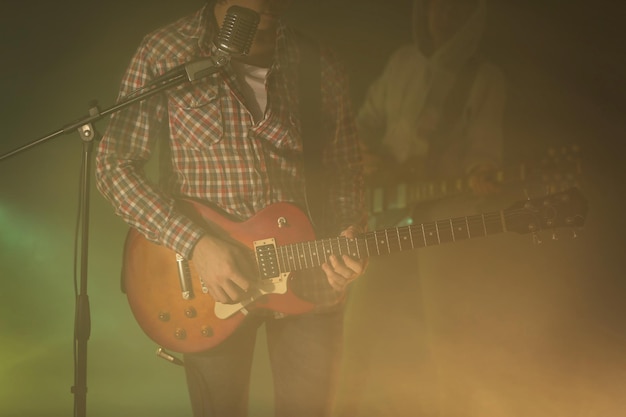 Jeune couple jouant de la guitare électrique sur fond brumeux éclairé