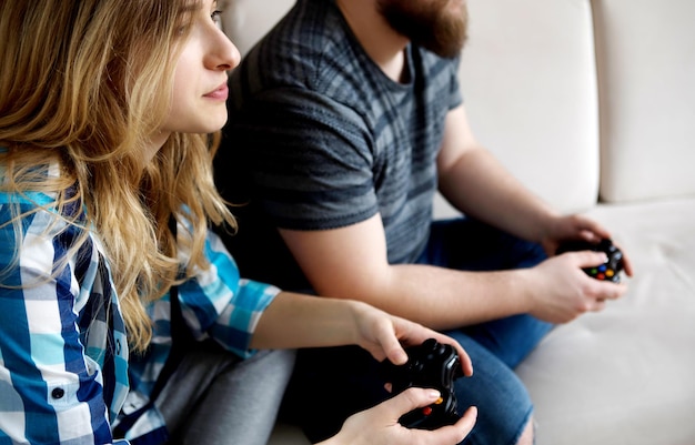 Un jeune couple joue à un jeu vidéo tout en se relaxant sur le canapé à la maison.