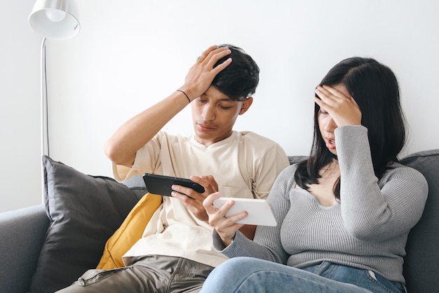 Photo un jeune couple joue à des jeux mobiles ensemble et perd le jeu en passant du temps ensemble dans le salon