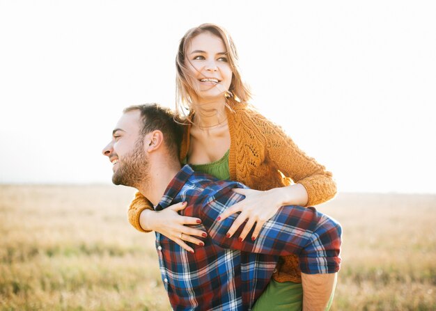 Jeune couple joyeux d'homme et de femme dans un champ ouvert, ferroutage.