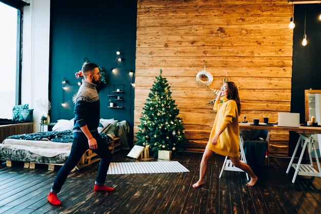 Jeune couple joyeux s'amusant tout en décorant un appartement