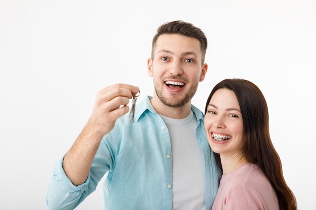 Un jeune couple joyeux se serre dans ses bras dans la cuisine en tenant les clés d'une nouvelle maison entre leurs mains Heureux les jeunes mariés ont emménagé dans un nouvel appartement ont obtenu une hypothèque le jour du déménagement