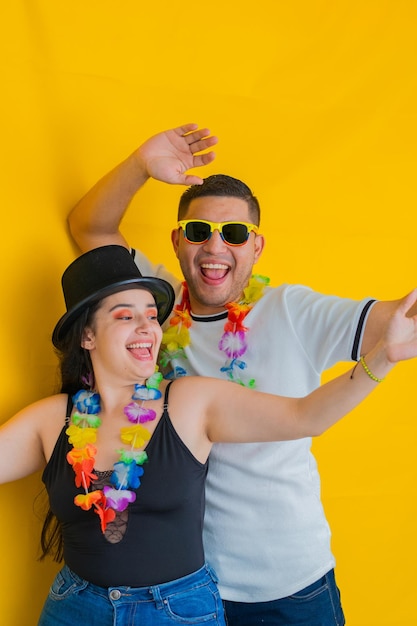 Photo un jeune couple latin danse en riant à haute voix derrière son fond jaune.