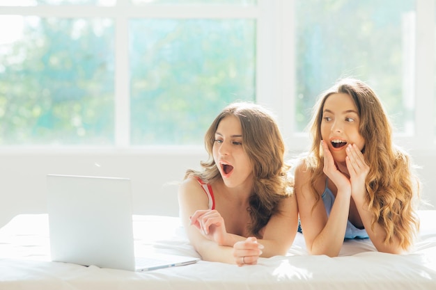 jeune couple de lesbiennes avec ordinateur portable sur le lit