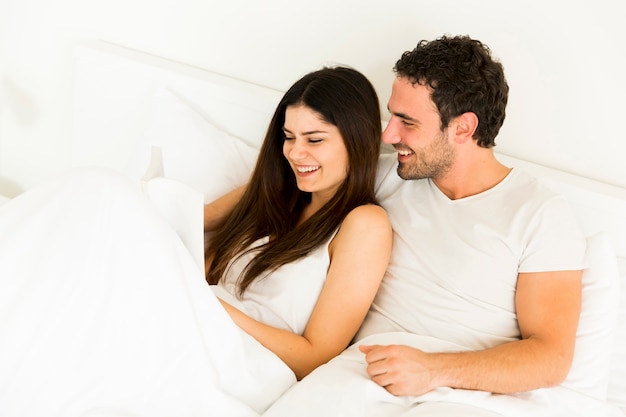 Jeune couple lisant un livre dans le lit