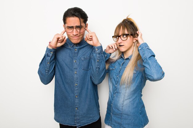 Jeune couple avec des lunettes couvrant les deux oreilles avec les mains