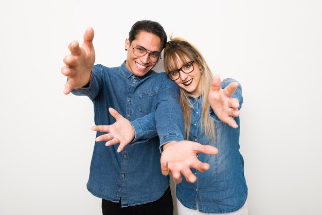 Jeune couple avec des lunettes présentant et invitant à venir avec la main