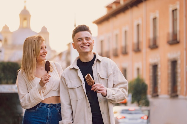 Un jeune couple mange de la glace en visitant une nouvelle ville en vacances