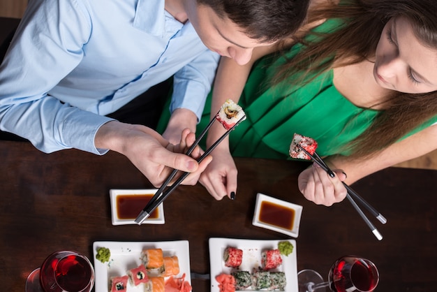 Jeune couple mange des sushis au restaurant.