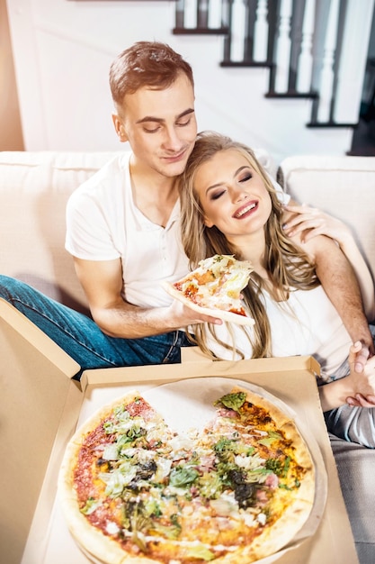 jeune couple, manger, pizza, sur, sofa, chez soi