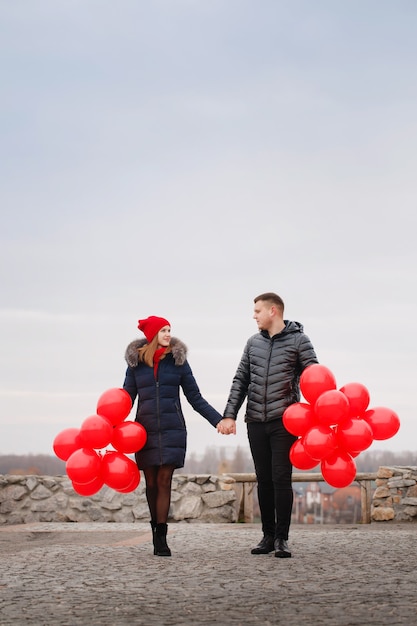 Jeune couple marchant avec des ballons rouges